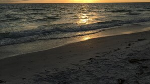 A beach with waves and a sunset.