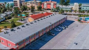A large building with a flat roof, multiple parking spaces, and a swimming pool area.