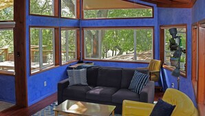 A room with a large window, a sofa, a yellow chair, and a coffee table.