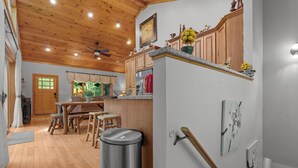 A kitchen with wooden cabinets, a stainless steel sink, and a ceiling fan. - Luxury Cabin | Hot Tub & Game Room Near Highlands (Franklin)
