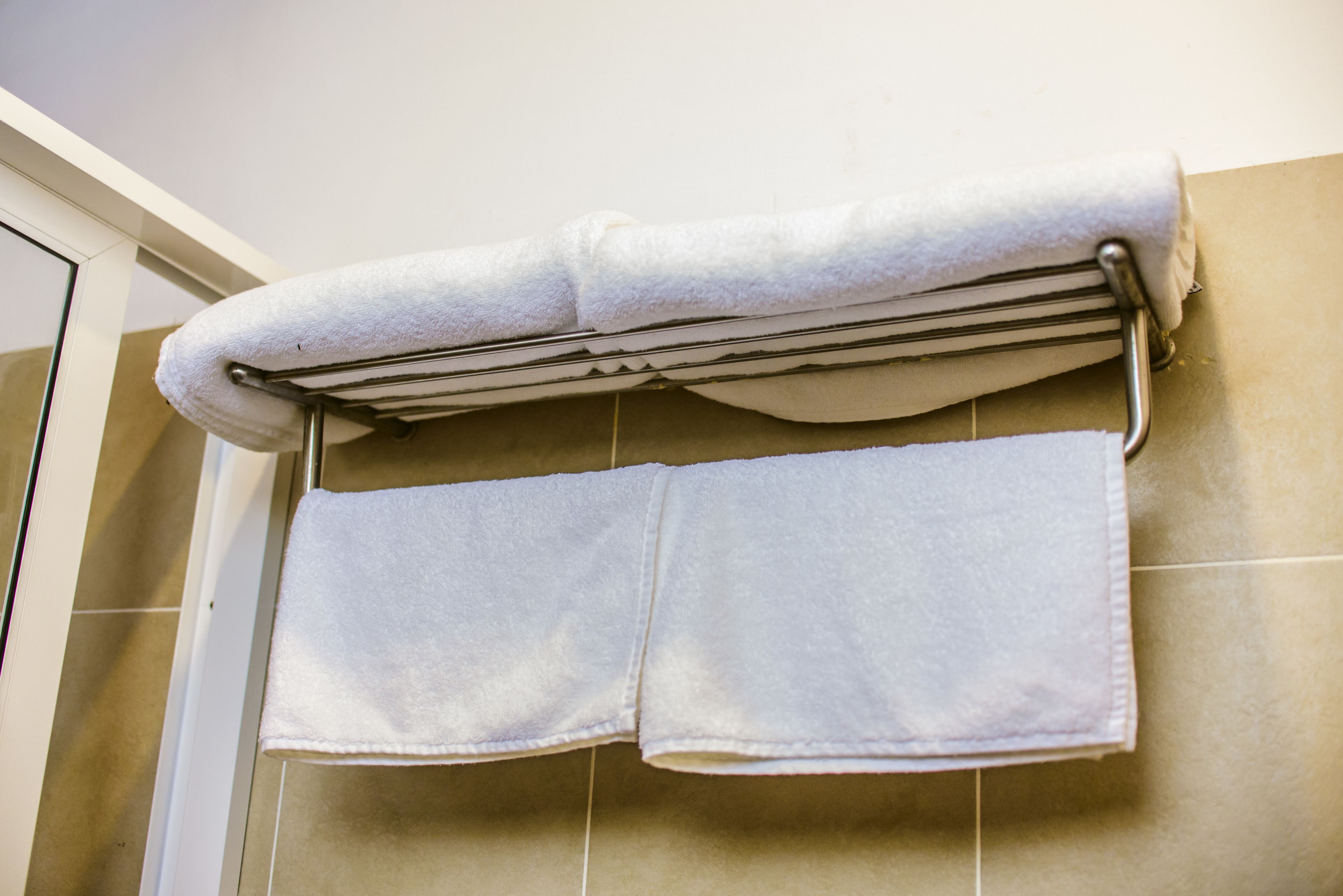 A bathroom with a towel rack holding two white towels.