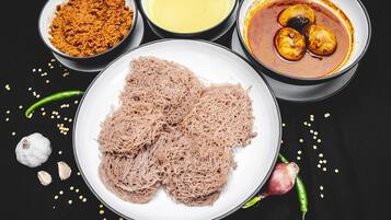 A plate of noodles, a bowl of curry, a bowl of spices, and a bowl of sauce.