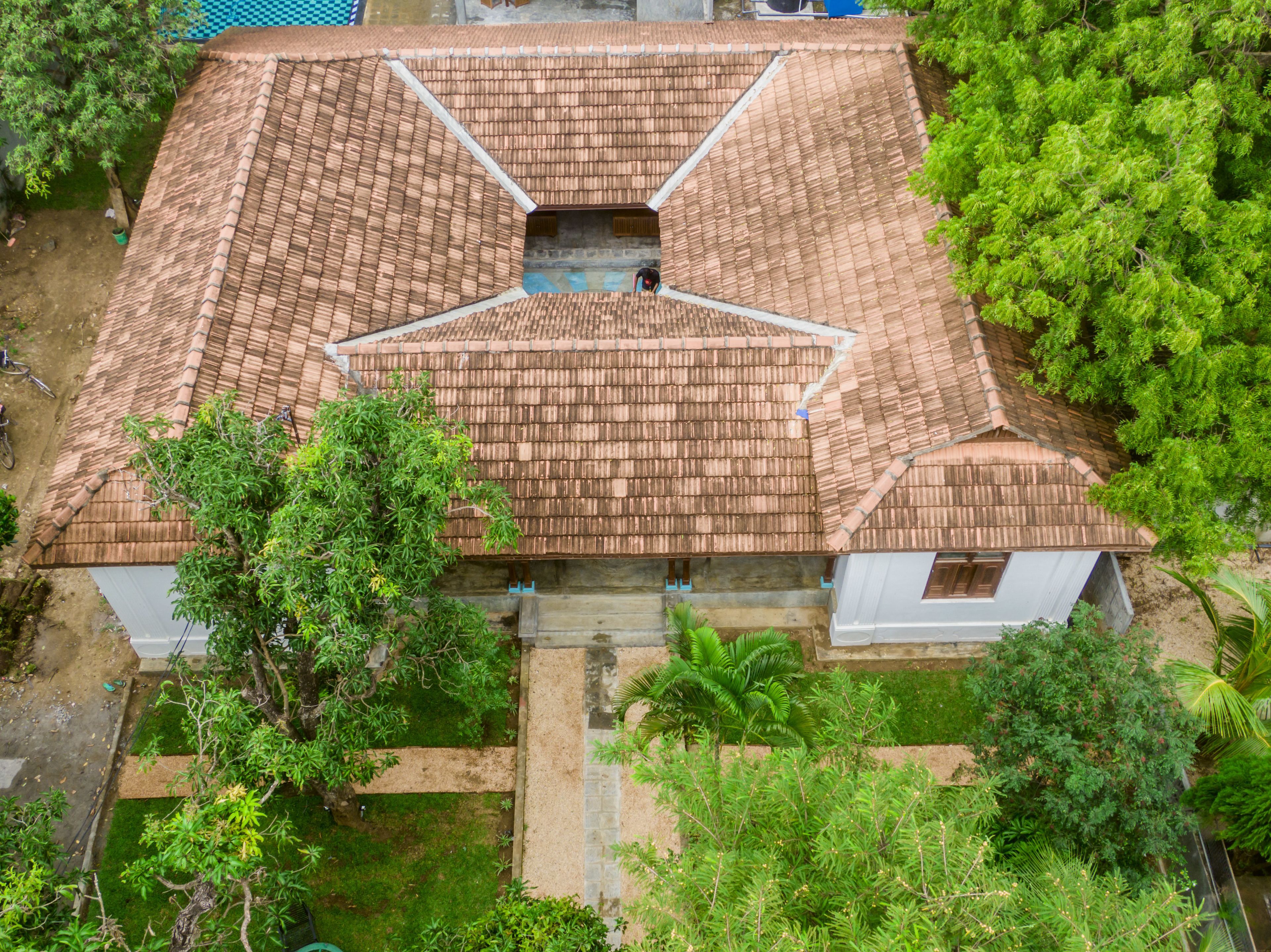 A house with a tiled roof, surrounded by greenery and a small garden area.