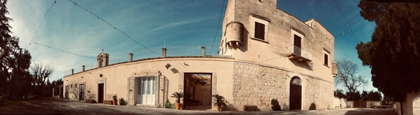 A historic building with a curved facade, large windows, and a balcony. - Masseria Chiusurella (Corato)