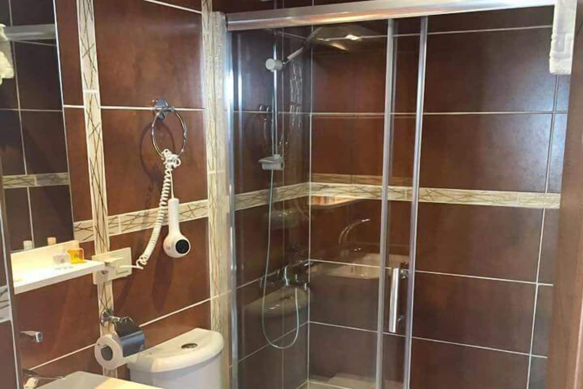 A bathroom with a shower, toilet, and sink.