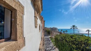 Un edificio con balcón que da a la costa, con vista al mar y palmeras.