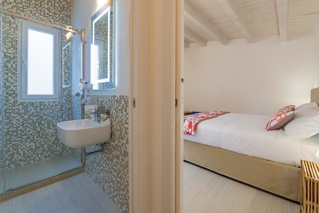 Un dormitorio con cama, mesita de noche y ventana.