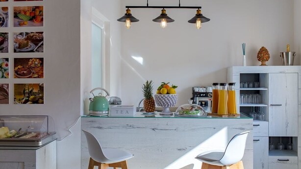Una cocina moderna con una isla de vidrio, armarios blancos y una cafetera.