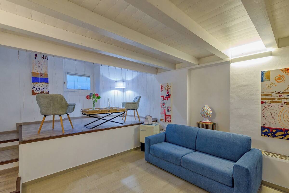 Ett modernt vardagsrum med en blå soffa, ett soffbord i trä och en matplats med stolar och ett bord.