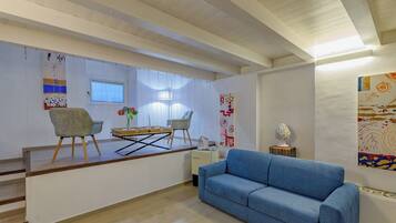 Una sala de estar moderna con un sofá azul, una mesa de centro de madera y un comedor con sillas y una mesa.