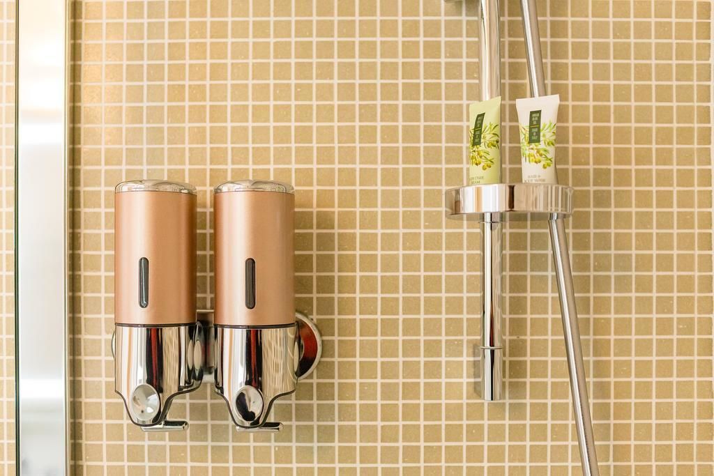 A bathroom with two chrome showerheads mounted on a tiled wall.