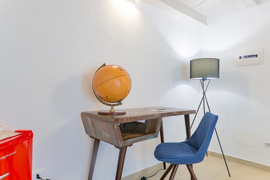 A room with a wooden desk, a globe, a blue chair, and a floor lamp.