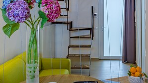 Una sala de estar moderna con una mesa de madera, un sofá y una escalera al fondo.