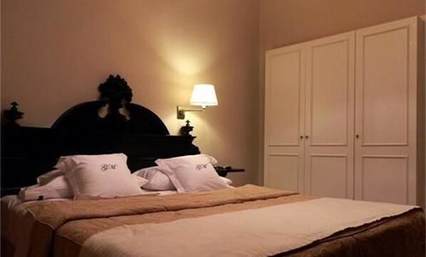 A hotel room with a bed, a nightstand, a lamp, and a wardrobe.