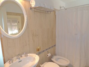A bathroom with two sinks, a toilet, a shower curtain, a towel rack, and a mirror.