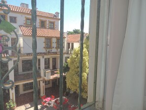 A courtyard with red chairs and tables, surrounded by buildings with terracotta roofs and white walls.