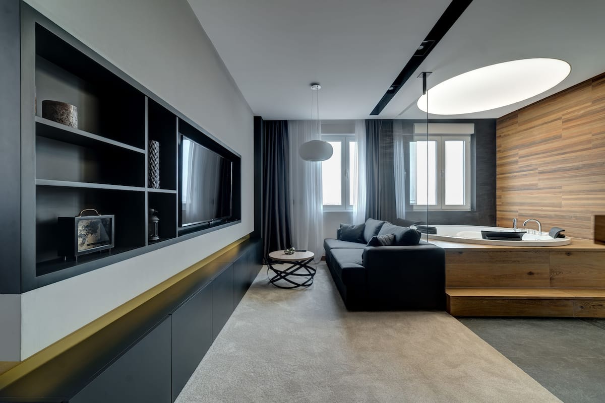 Ein modernes Wohnzimmer mit einer Couch, einem Couchtisch und einem Fernseher auf einem schwarzen Regal.