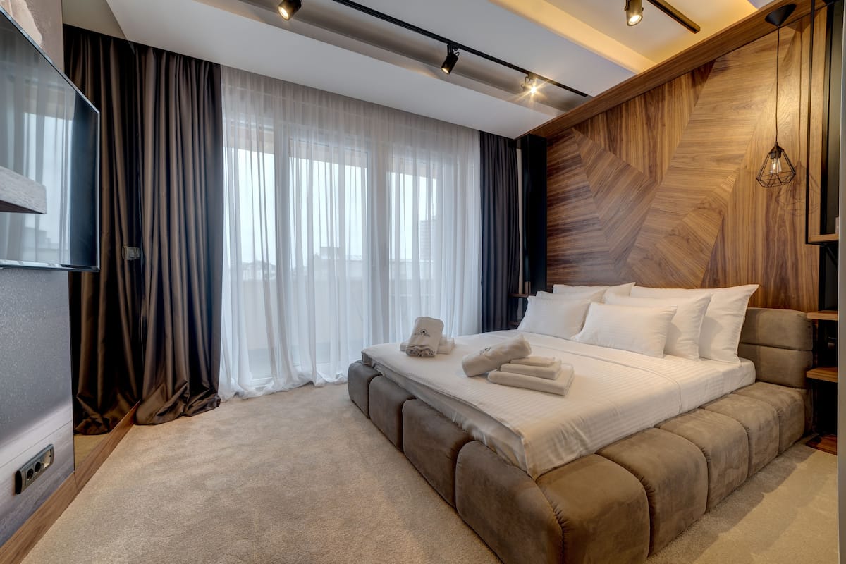 Ein modernes Schlafzimmer mit einem großen Bett, einem Flachbildfernseher und einer Wand mit Holzverkleidung.