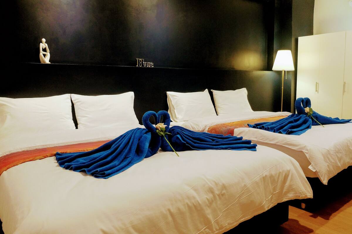 A hotel room with two beds, each with white linens and blue towels.