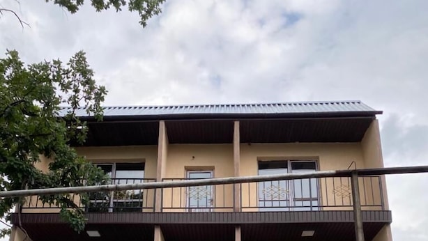 A multi-story residential building with a balcony on the upper floor, a front door, and a small staircase leading to the entrance. - Pana Inn (Almaty)