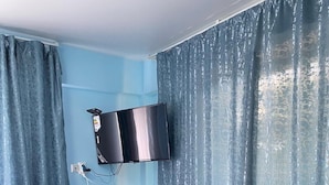 A small room with a flat-screen TV mounted on the wall, a small table with a water dispenser, and a power outlet. - Pana Inn (Almaty)