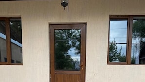 A building entrance with a wooden door, a set of stone steps, and a doormat. - Pana Inn (Almaty)