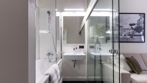 A modern bathroom with a glass shower enclosure, a white sink, and a beige sofa.