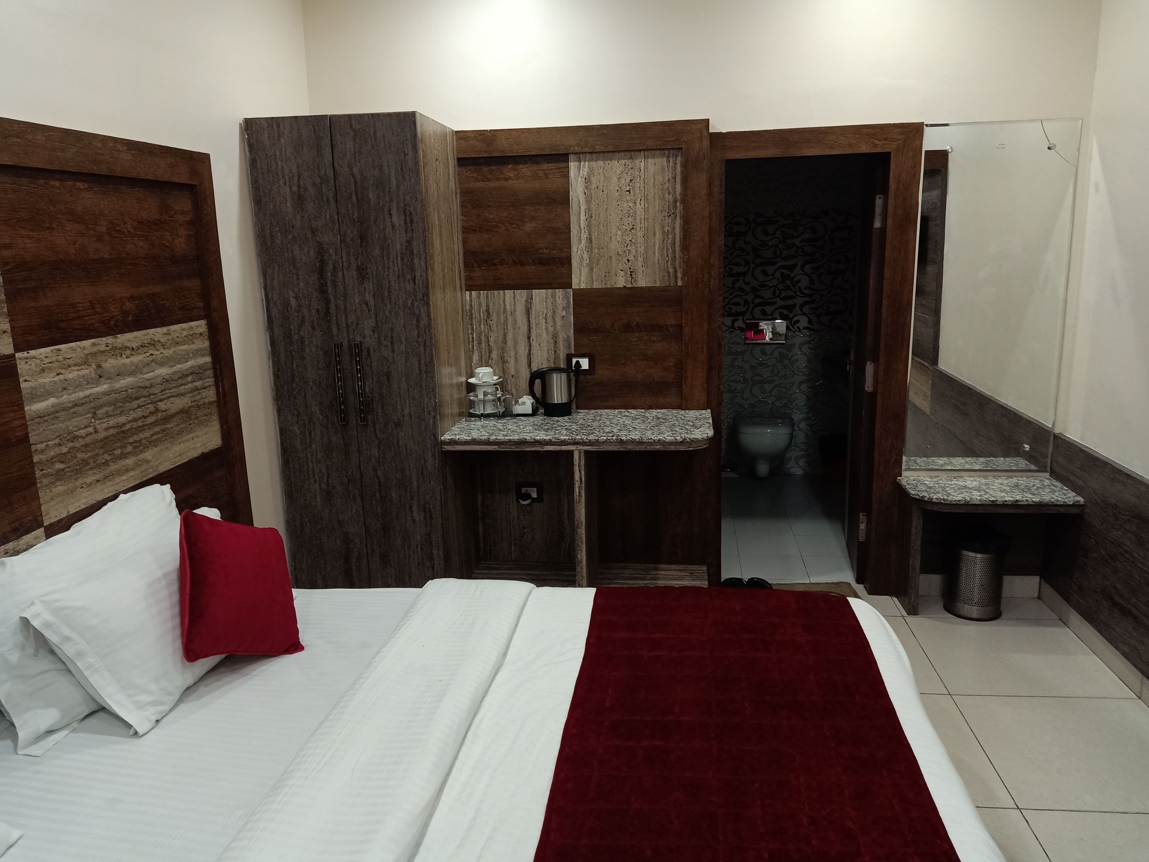 A hotel room with a bed, a wardrobe, a small bathroom, and a sink.
