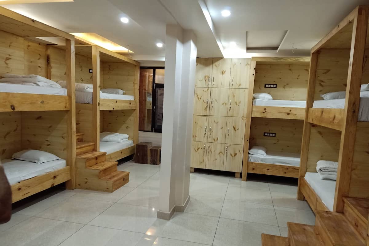 A room with bunk beds, wooden lockers, and a tiled floor.