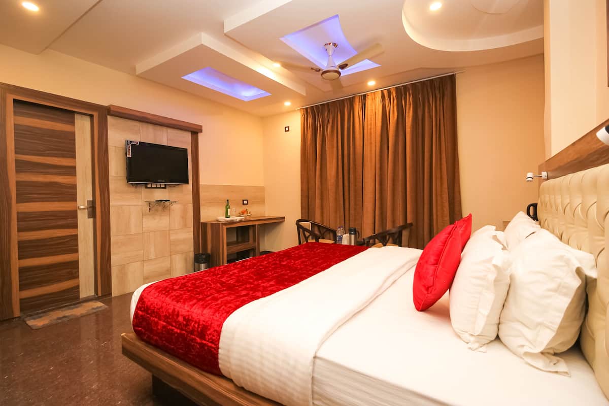A hotel room with a bed, a TV, a desk, and a bathroom.