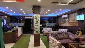 Un vestíbulo de hotel con mostrador de recepción, zona de estar y una estatua de Buda.