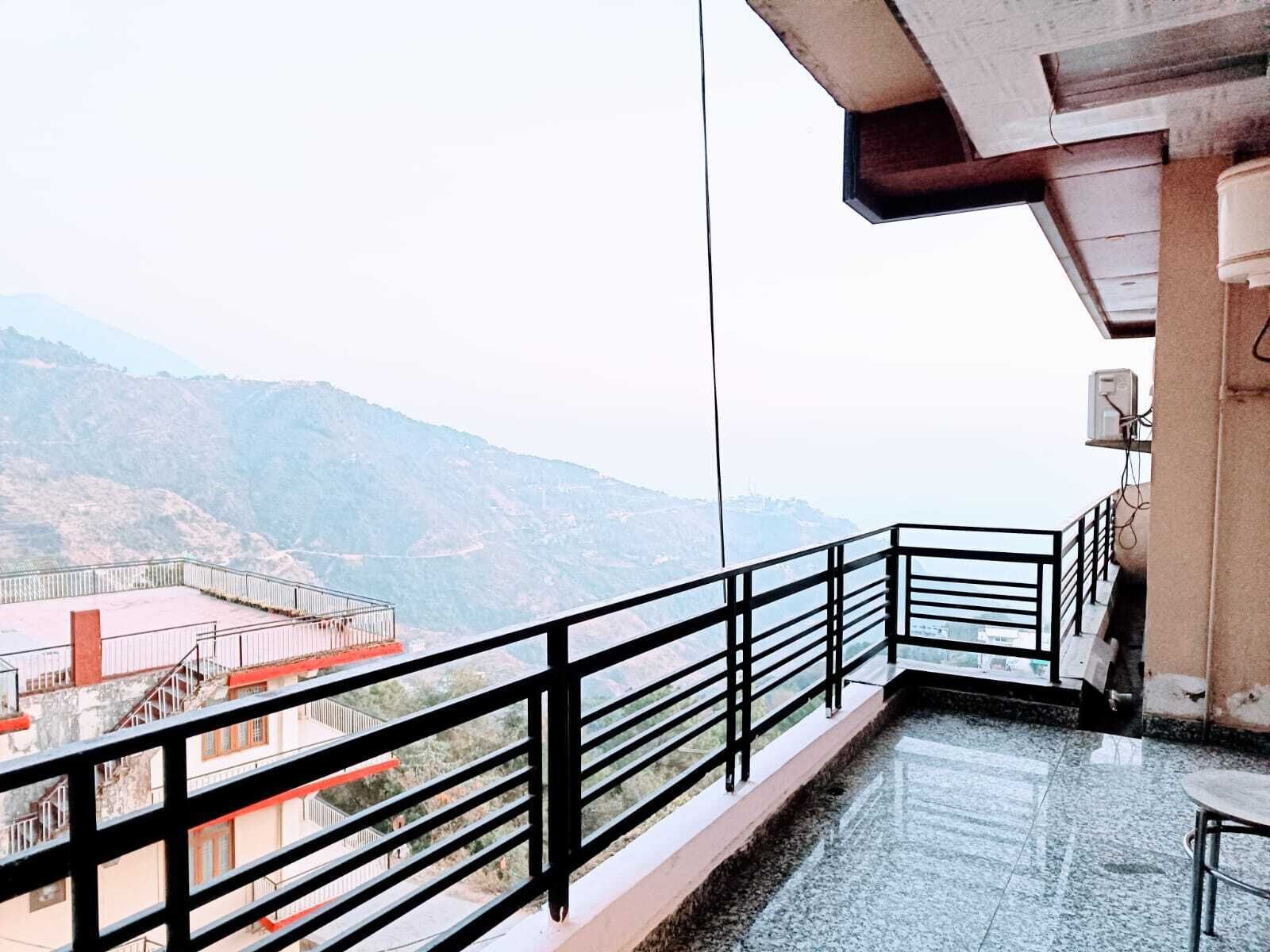 A balcony with a metal railing overlooking a mountainous landscape.