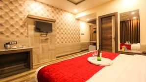 Una habitación de hotel moderna con una cama grande, un televisor de pantalla plana en la pared, un escritorio de madera y una pared de acento roja.