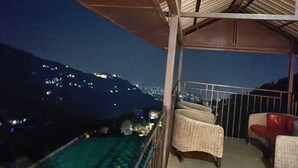 Un balcón con mobiliario de mimbre y vista a la ciudad de noche.