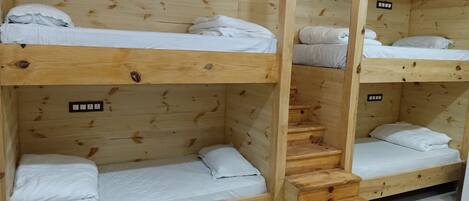 A bunk bed room with wooden walls and a staircase.