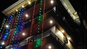 Un edificio de varios pisos con balcones, unidades de aire acondicionado y luces colgantes.