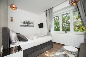 A modern bedroom with a bed, a TV, and a window with curtains.