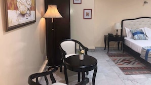 A hotel room with a bed, a desk with a chair, a lamp, and framed pictures on the wall. - Résidence De L'Amitié (Dakar)