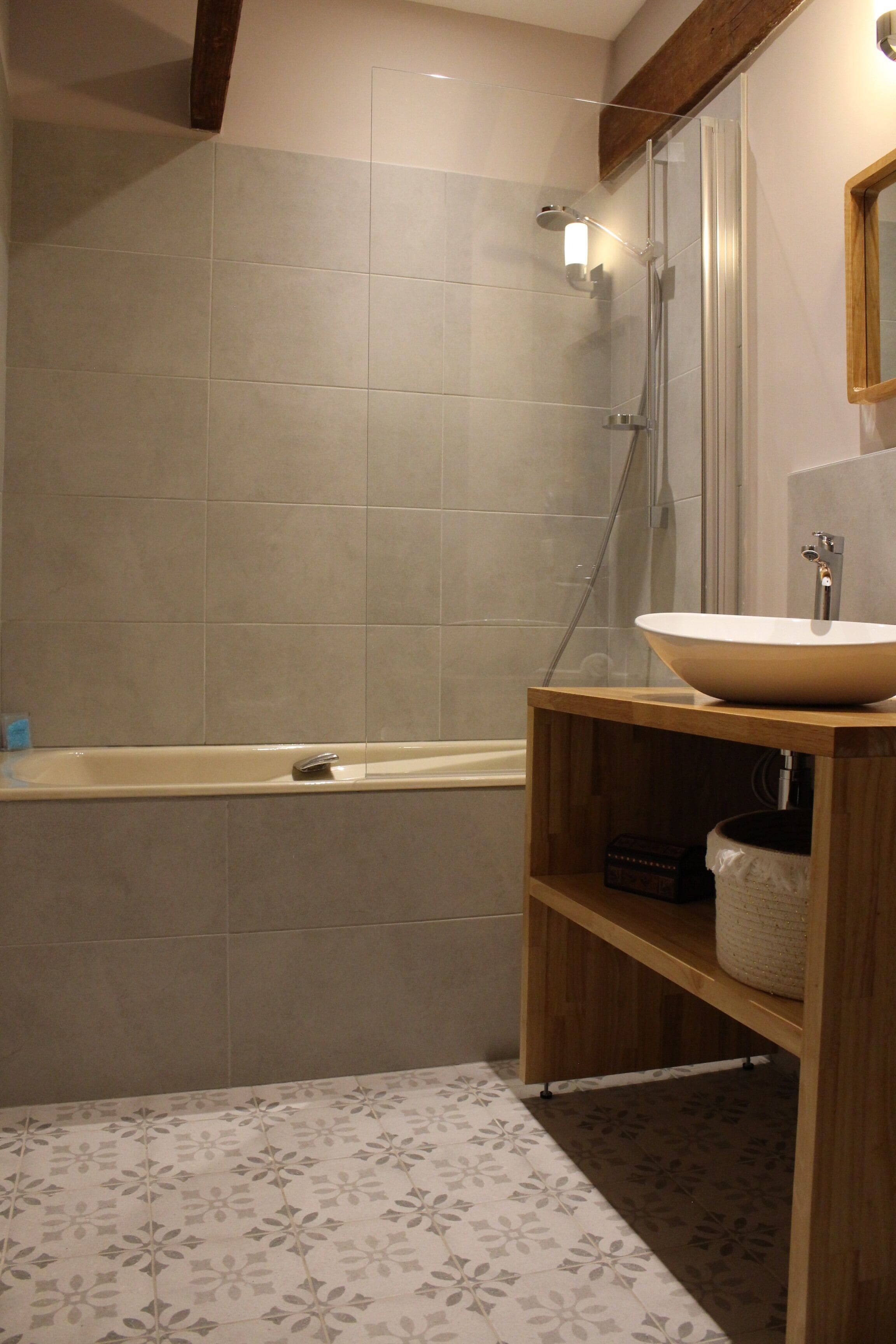 A bathroom with a bathtub, a wooden vanity with a sink, and a shower area.
