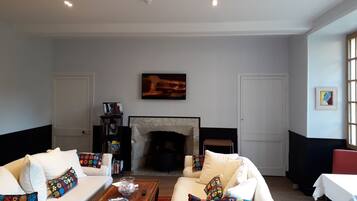 A living room with a fireplace, sofas, a coffee table, and a television.