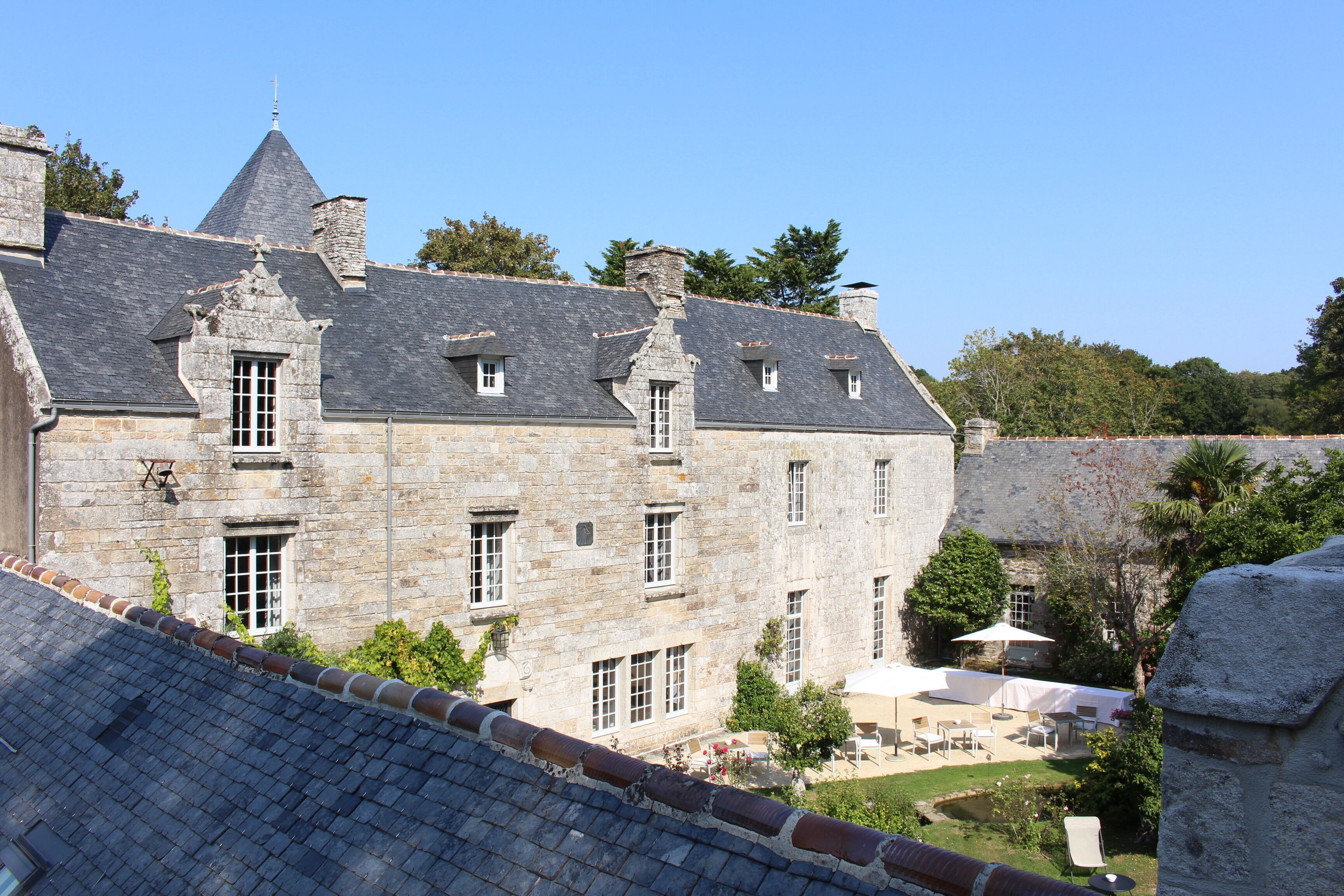 A stone building with multiple windows and a courtyard with outdoor seating.