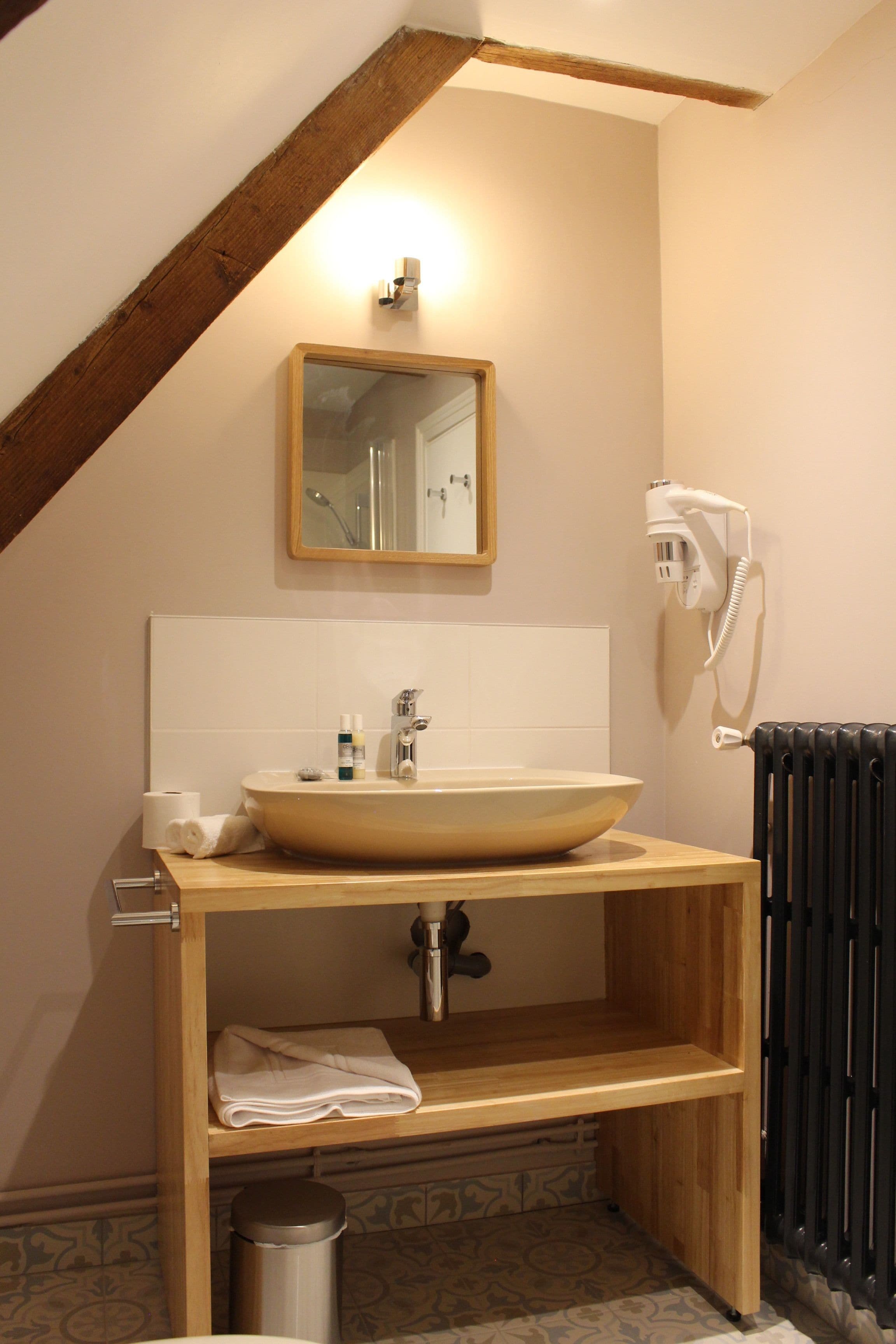 Un baño con tocador de madera, un lavabo grande, un espejo, un perchero para toallas y un radiador.