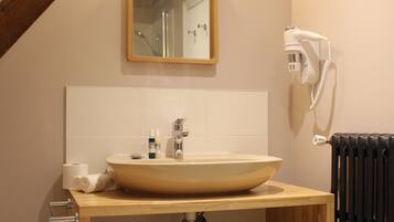 Un baño con tocador de madera, un lavabo grande, un espejo, un perchero para toallas y un radiador.