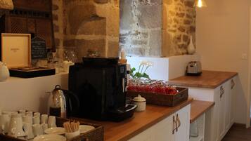 A kitchen with stone walls, wooden countertops, hanging pendant lights, and various kitchen appliances and utensils.