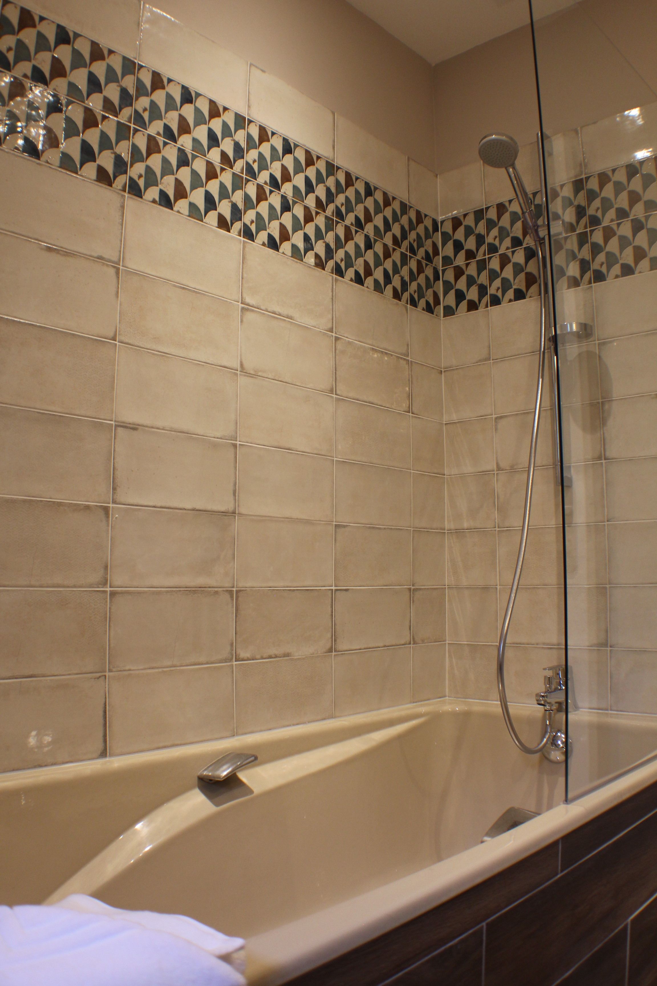Ein Badezimmer mit Badewanne, Dusche und gefliesten Wänden.