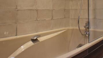 Ein Badezimmer mit Badewanne, Dusche und gefliesten Wänden.