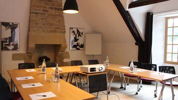 A conference room with a long table, chairs, a projector, and a fireplace.