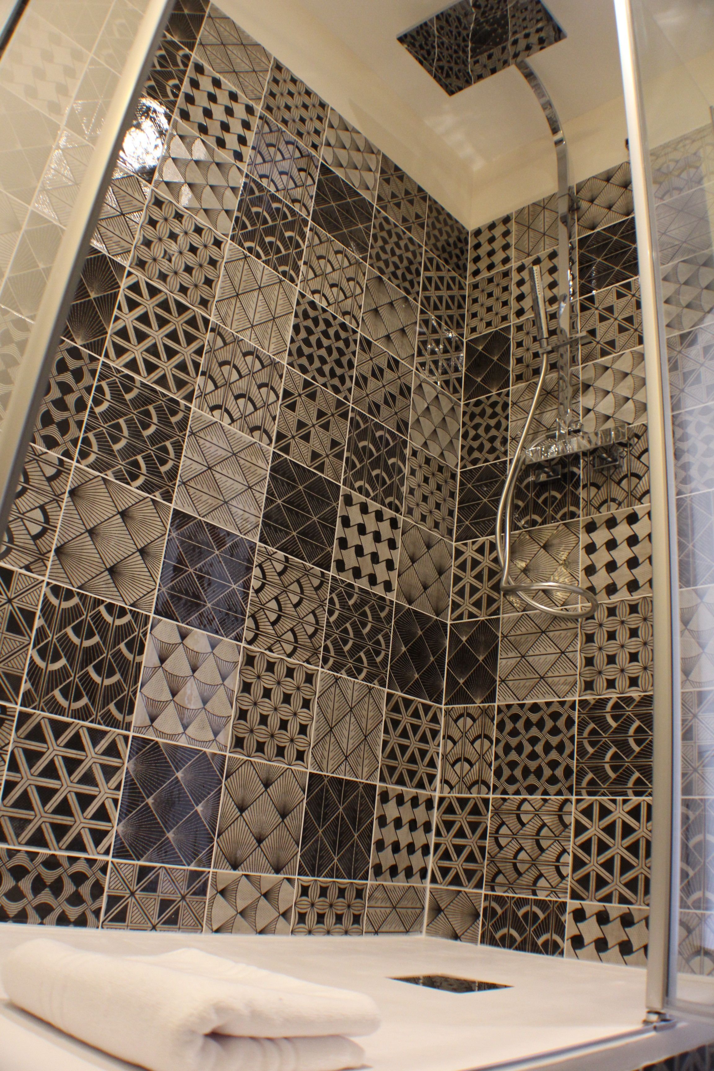 Una ducha con un patrón de azulejos geométricos y desagüe visible.