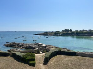Une zone côtière avec des bateaux sur l’eau, un terrain rocheux et un ciel dégagé.