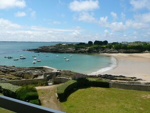 Une vue sur la côte, avec des bateaux sur l’eau, une plage de sable et un paysage rocheux.